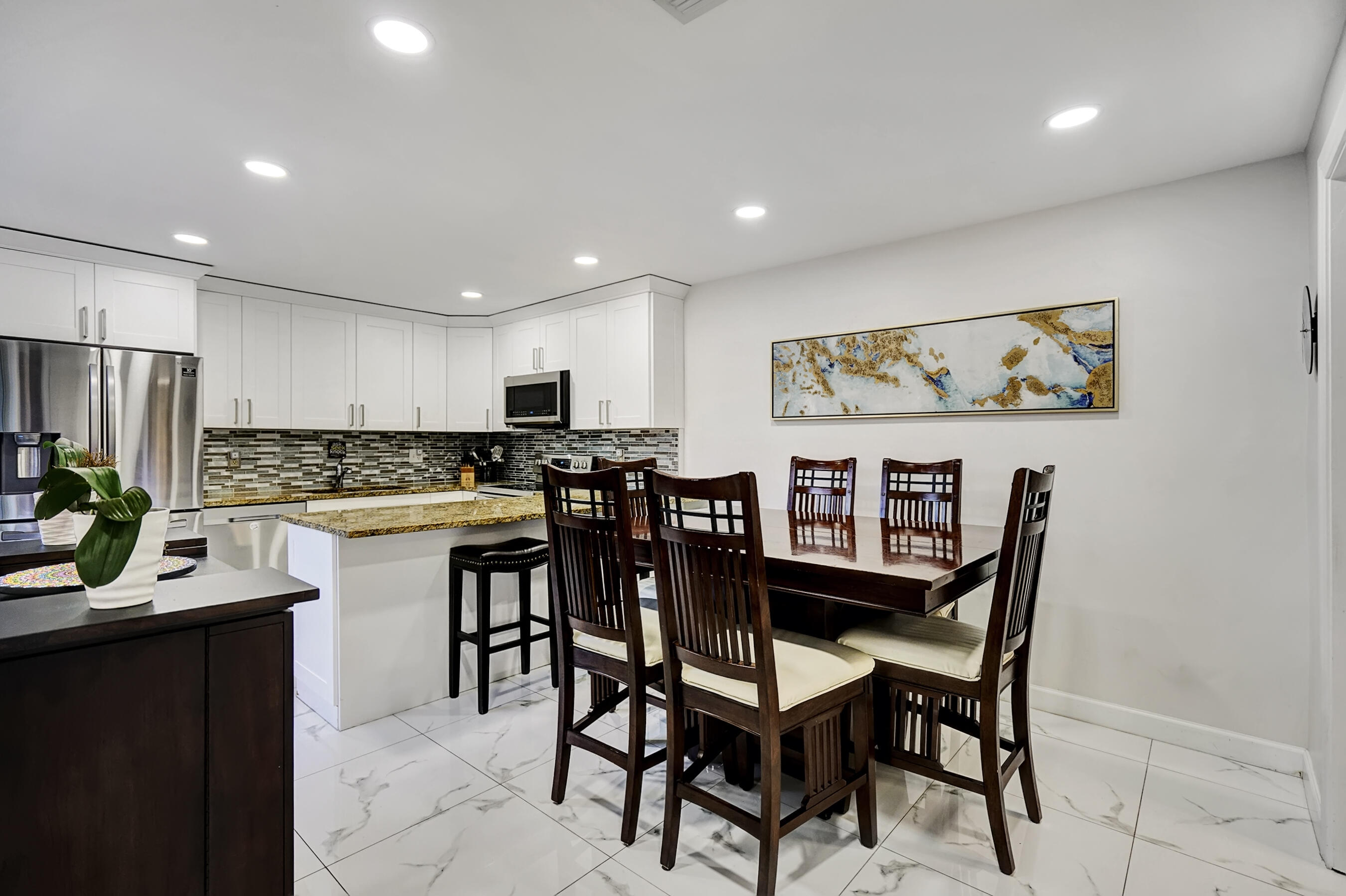 22176 Boca Rancho Drive, Unit C Boca Raton, FL 33428 - Photo 4 of 34 a kitchen with stainless steel appliances kitchen island granite countertop a dining table chairs and a refrigerator