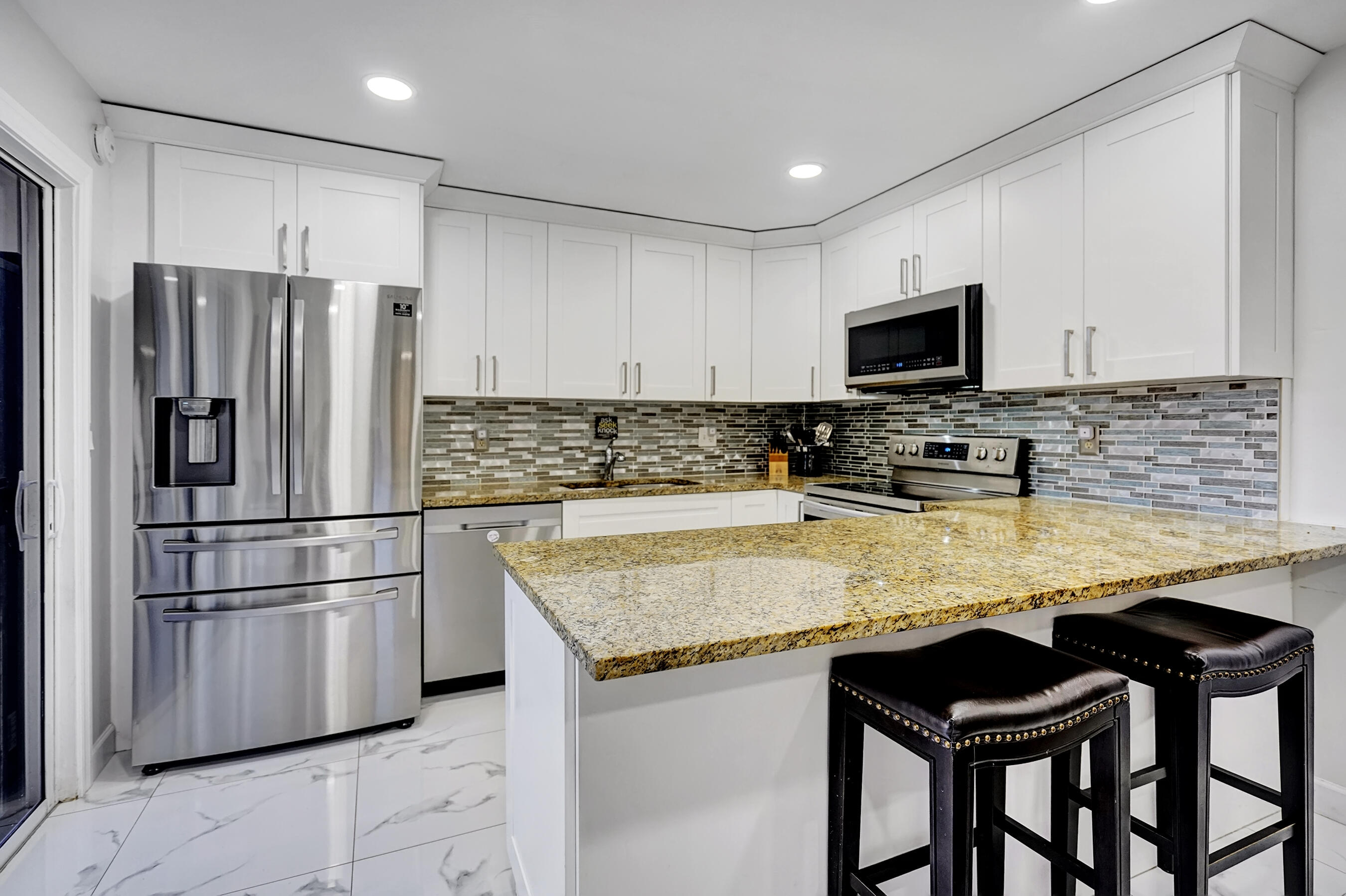 22176 Boca Rancho Drive, Unit C Boca Raton, FL 33428 - Photo 6 of 34 a kitchen with granite countertop a refrigerator stove microwave and cabinets