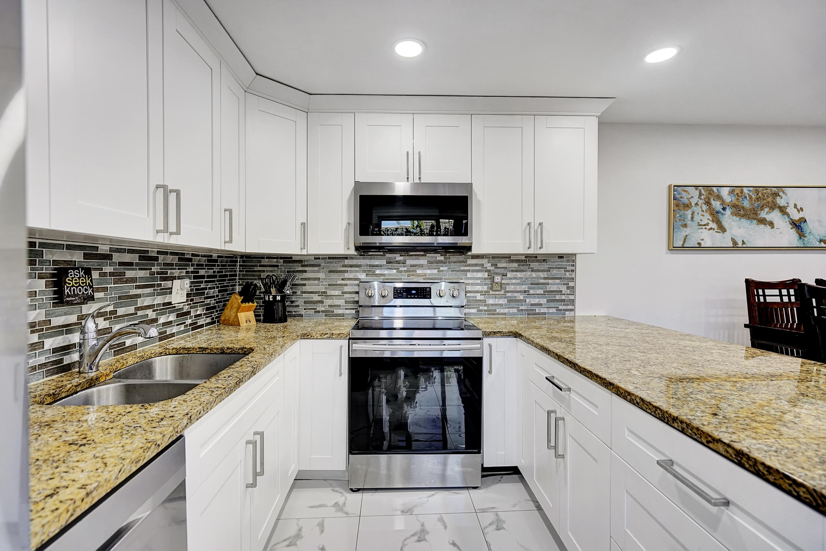 22176 Boca Rancho Drive, Unit C Boca Raton, FL 33428 - Photo 7 of 34 a kitchen with granite countertop a sink stainless steel appliances and white cabinets