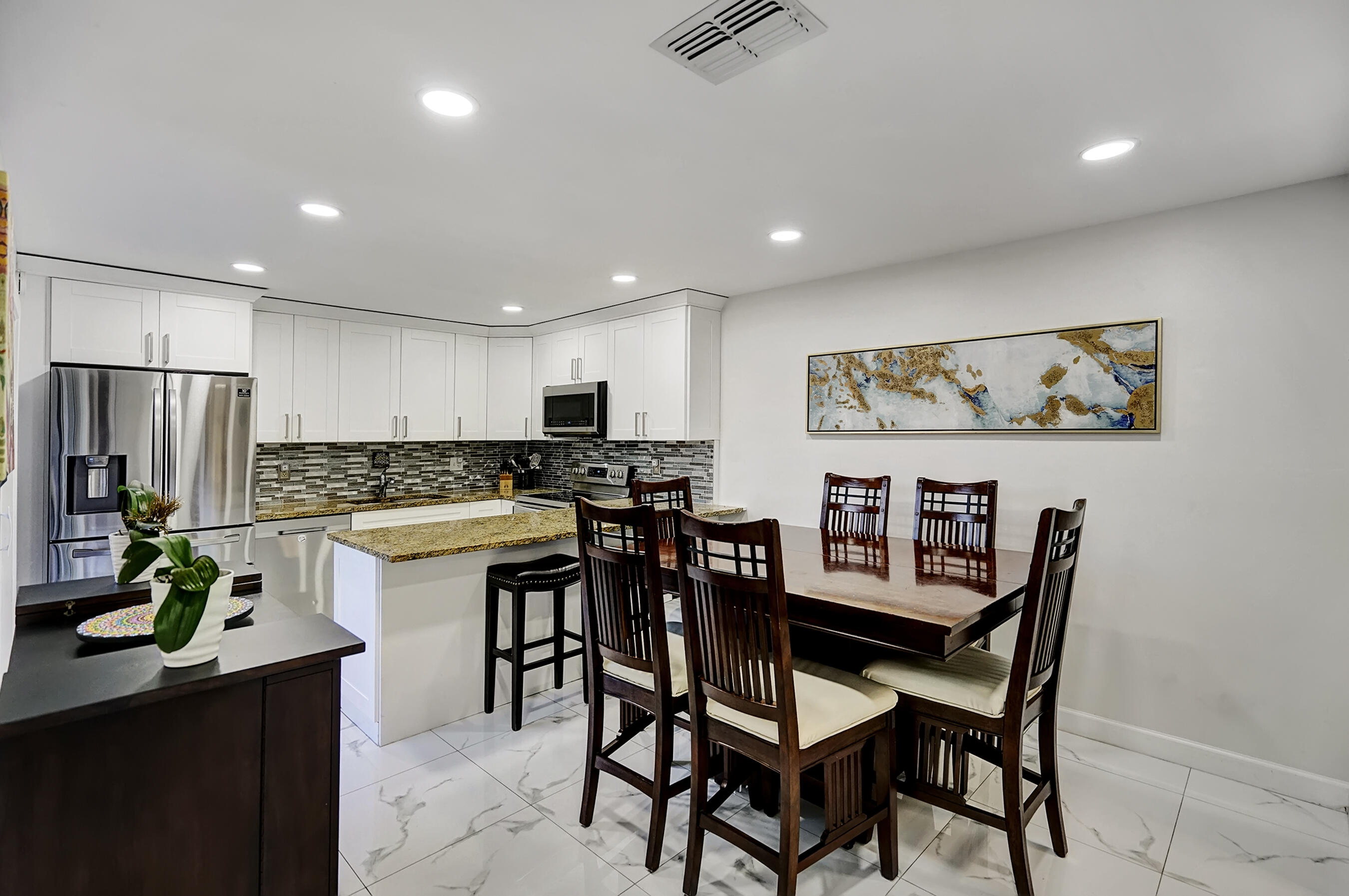 22176 Boca Rancho Drive, Unit C Boca Raton, FL 33428 - Photo 10 of 34 a kitchen with stainless steel appliances kitchen island granite countertop a dining table chairs and a refrigerator