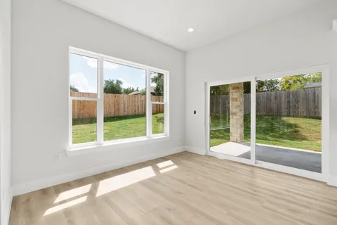 a view of an empty room with wooden floor and glass door