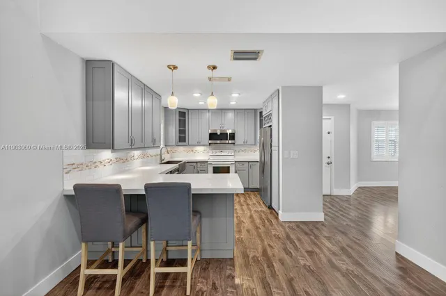 a kitchen with stainless steel appliances kitchen island granite countertop a table chairs sink and cabinets