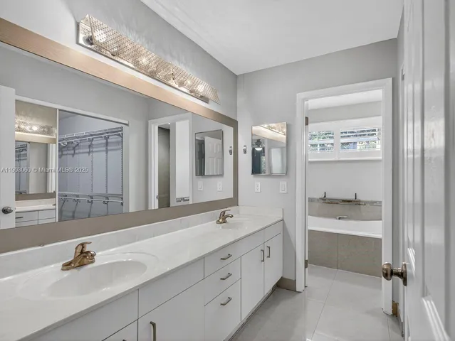 a spacious bathroom with a double vanity sink a mirror and a bathtub