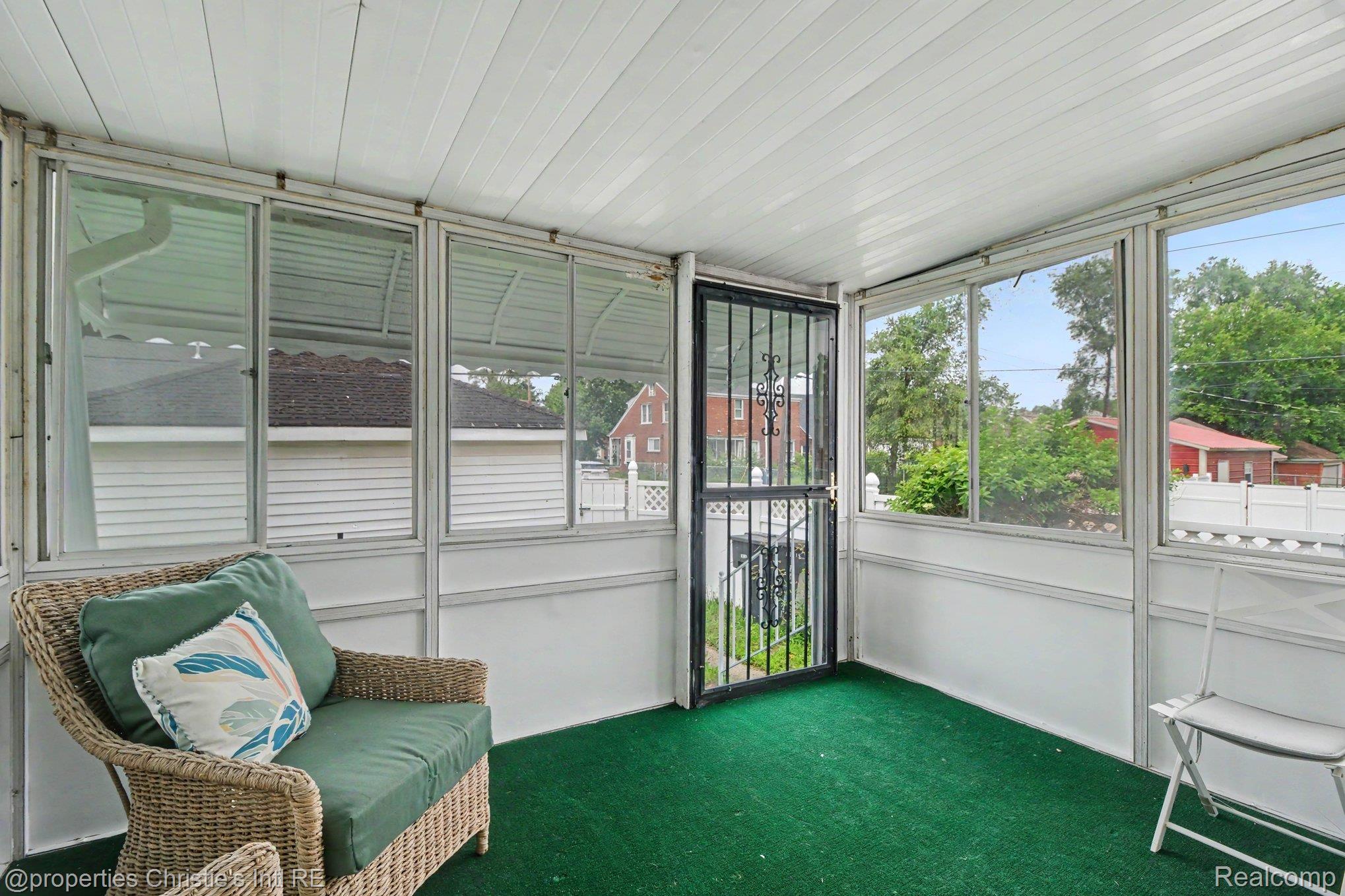 18315 Prairie Street Detroit, MI 48221 - Photo 7 of 16 Enclosed porch featuring a white panel ceiling, multiple window panels, a security screen door, and green floor covering