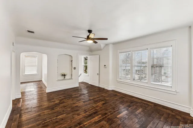 a view of an empty room with a window and wooden floor