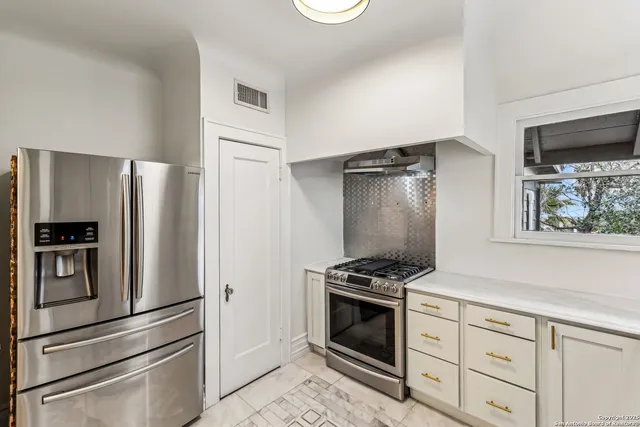 a kitchen with stainless steel appliances white cabinets and a stove top oven