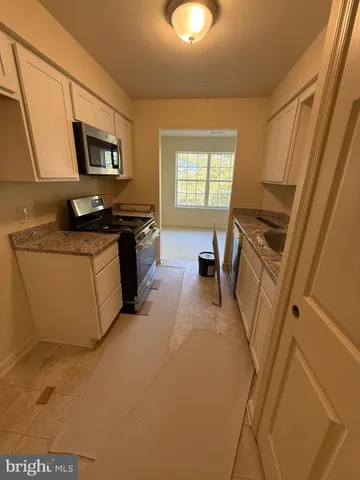 a kitchen with stainless steel appliances a refrigerator a sink a stove top oven a counter space and cabinets