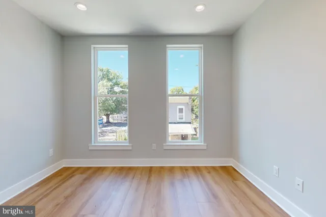 an empty room with wooden floor and windows