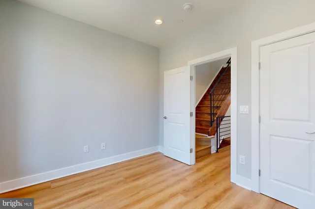 a view of an empty room with wooden floor and stairs