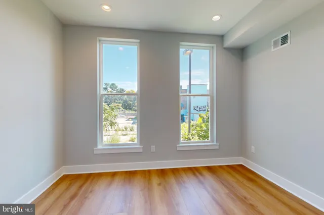 a view of empty room with wooden floor and fan