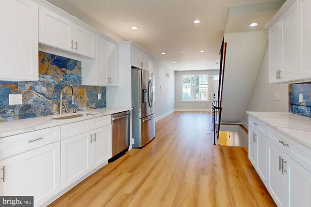 a kitchen with stainless steel appliances a refrigerator a sink dishwasher and a stove with wooden floor