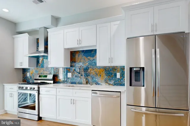 a kitchen with stainless steel appliances white cabinets and a refrigerator