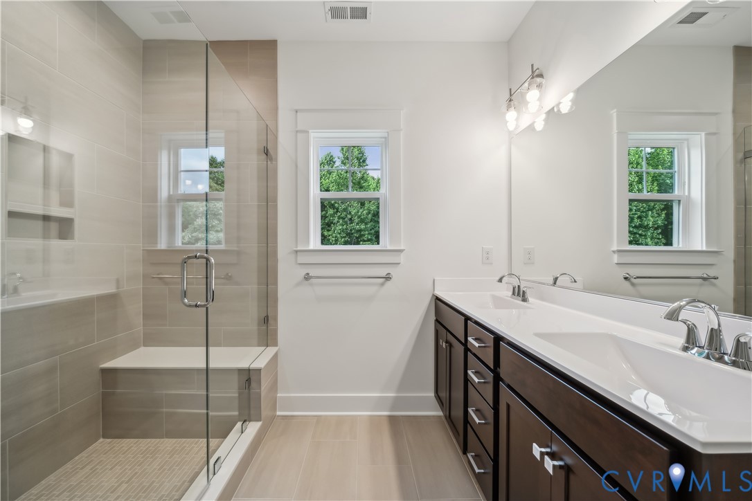 114 Logan Way Tappahannock, VA 22560 - Photo 19 of 28 a bathroom with a double vanity sink a large mirror and shower