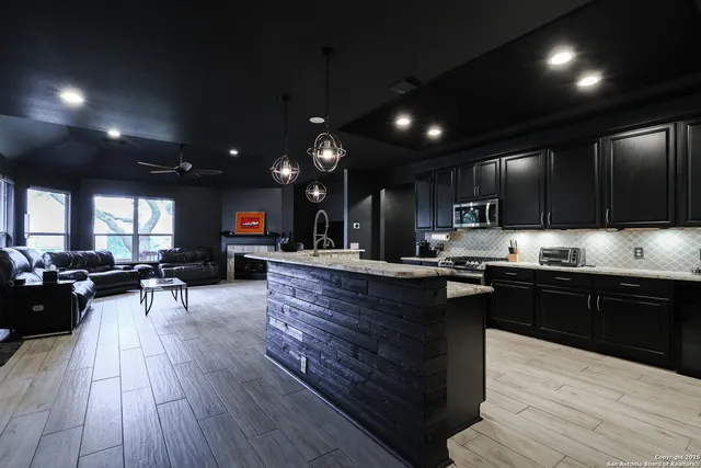 a kitchen with stainless steel appliances granite countertop wooden floors a stove and a granite counter top