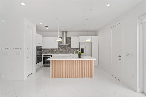a view of kitchen with kitchen island a stove a sink dishwasher and a refrigerator with wooden floor