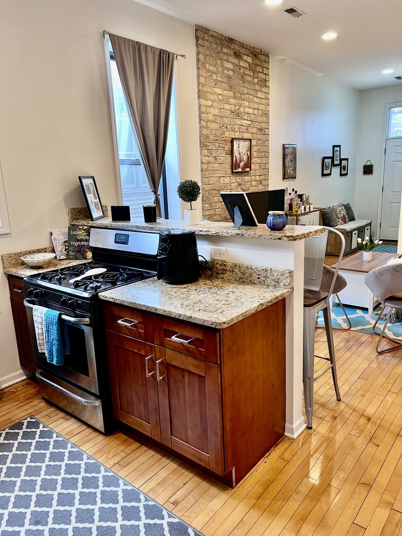 1421 West Huron Street, Unit 2R Chicago, IL 60642 - Photo 7 of 19 a kitchen with stainless steel appliances granite countertop a stove a sink and a microwave
