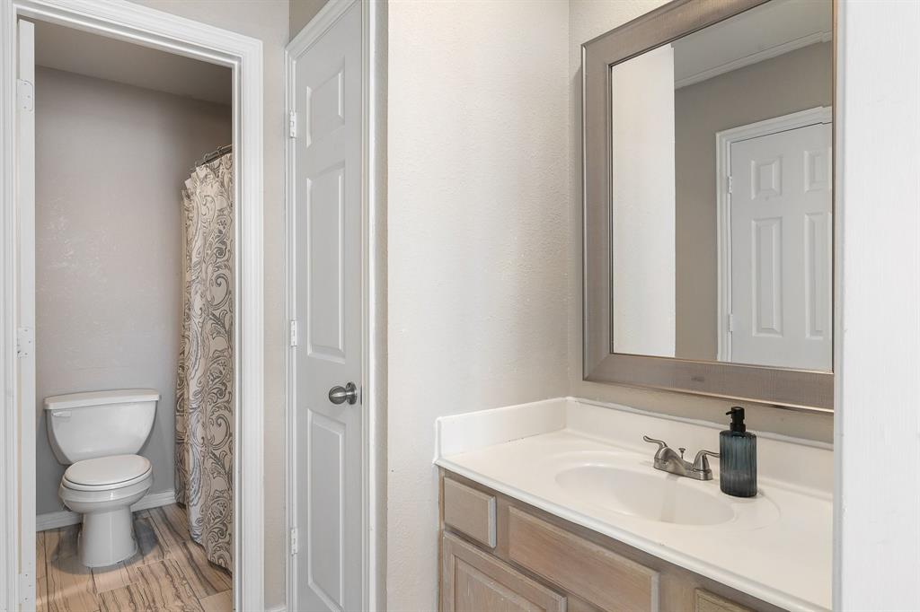18240 Midway Road, Unit 1301 Dallas, TX 75287 - Photo 19 of 25 Bathroom featuring a single vanity with an undermount sink, a framed mirror, and wood-finish flooring
