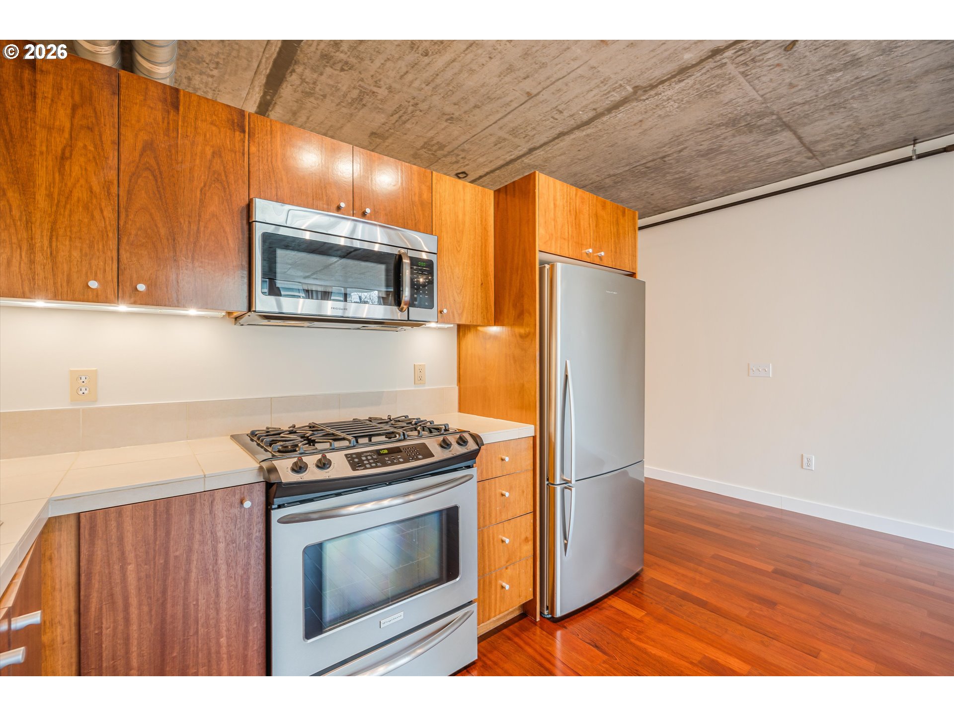 1926 West Burnside Street, Unit 512 Portland, OR 97209 - Photo 11 of 18 a kitchen with stainless steel appliances wooden floor sink stove and microwave