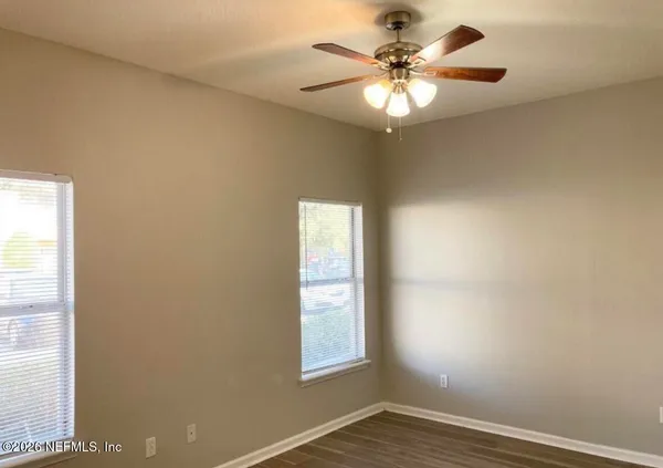 an empty room with windows and chandelier fan