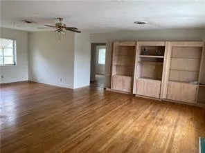 an empty room with wooden floor staircase and windows