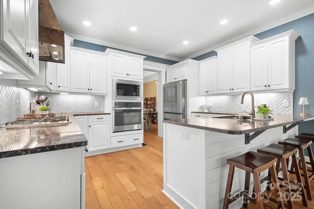 a kitchen with kitchen island granite countertop white cabinets and refrigerator