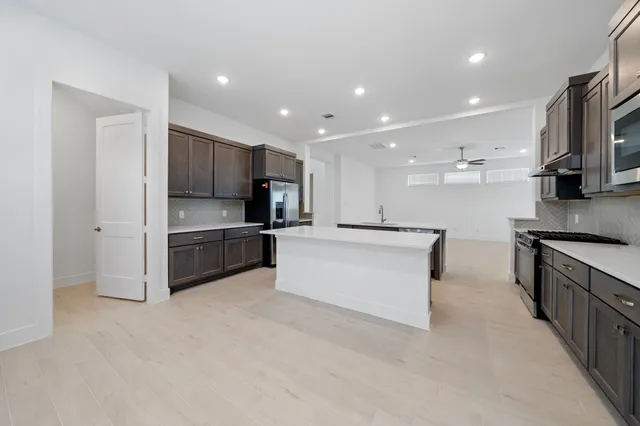 a large kitchen with stainless steel appliances kitchen island a large counter top and a stove top oven