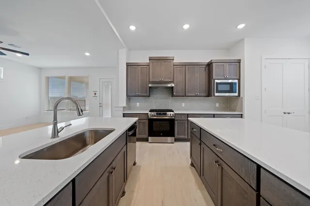 a kitchen with stainless steel appliances granite countertop a sink stove and cabinets