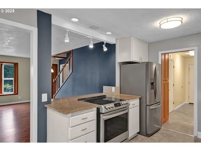 a kitchen with stainless steel appliances granite countertop a refrigerator a stove and a sink with wooden floor