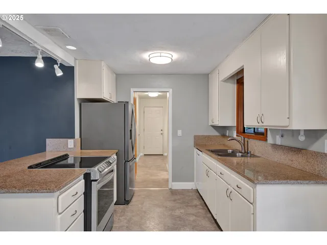 a kitchen with granite countertop kitchen island stainless steel appliances a sink stove and refrigerator