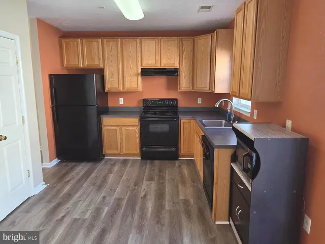 a kitchen with a refrigerator stove and wooden cabinets
