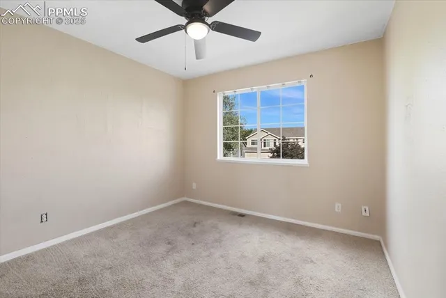 an empty room with a window and ceiling fan