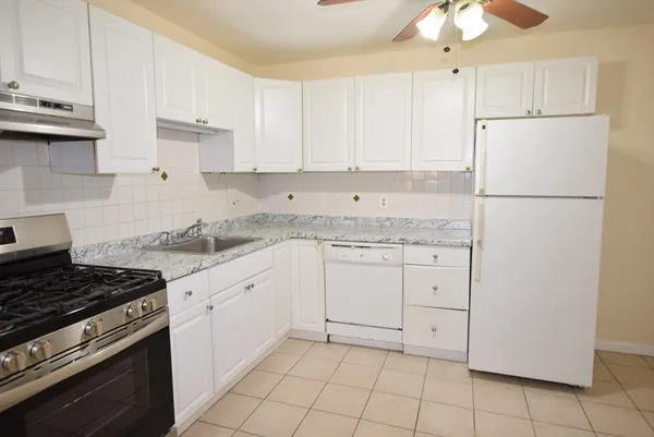 a kitchen with granite countertop white cabinets and white appliances
