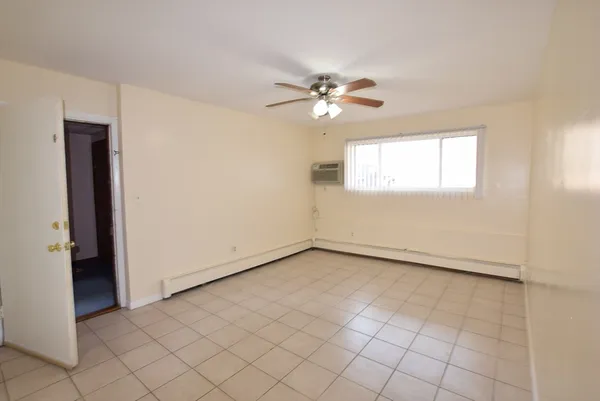 an empty room with windows and fan