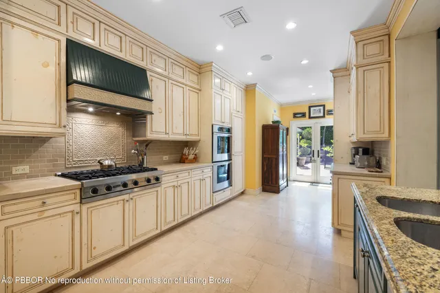 a kitchen with stainless steel appliances granite countertop a stove top oven a sink a refrigerator and white cabinets