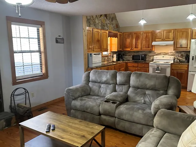 a living room with a couches and kitchen view with wooden floor