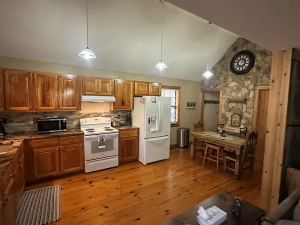 a kitchen with a refrigerator a stove top oven a sink dishwasher and dining table with wooden floor