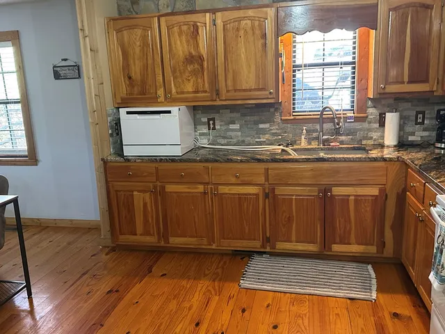 a kitchen with granite countertop wooden cabinets a sink and dishwasher
