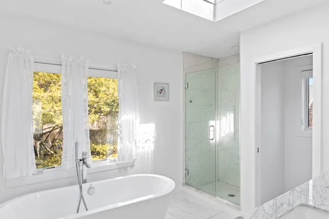 a bathroom with a tub shower and window