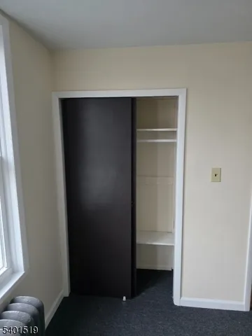 a view of an empty room with wooden floor and closet