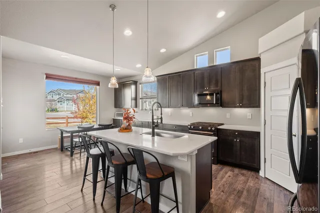 a kitchen with stainless steel appliances granite countertop a table chairs stove and refrigerator