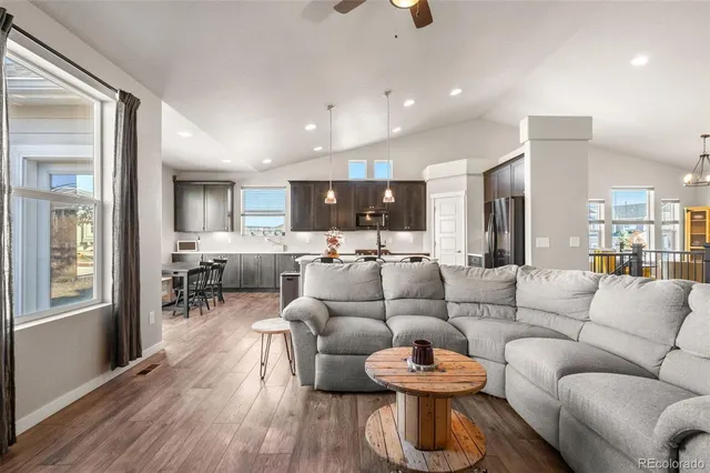 a living room with furniture kitchen view and a wooden floor