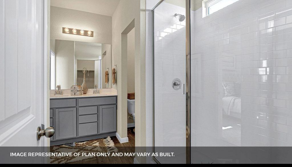 156 Docile Loop San Marcos, TX 78666 - Photo 4 of 40 The sleek glass shower enclosure with white subway tile offers a modern bathing experience in this well-appointed bathroom.