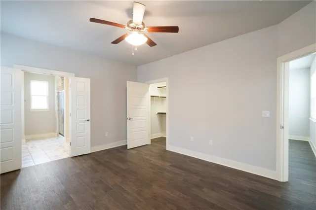 an empty room with wooden floor and ceiling fan
