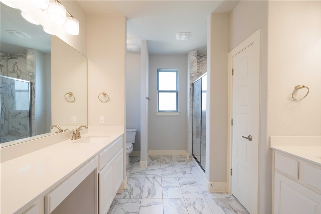 9124 Cattle Baron Path Austin, TX 78747 - Photo 15 of 36 a spacious bathroom with a double vanity sink a mirror and a shower