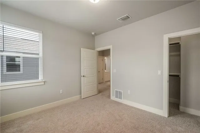 a view of an empty room with closet and a window