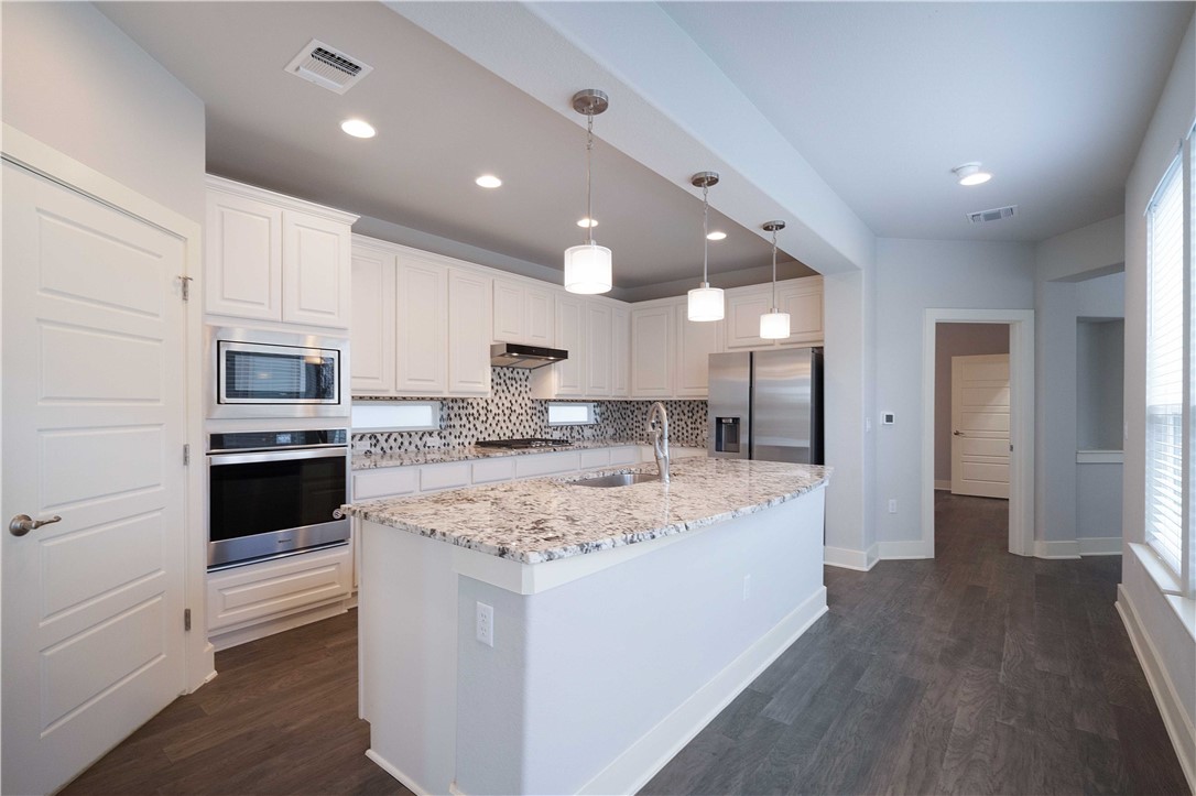9124 Cattle Baron Path Austin, TX 78747 - Photo 6 of 36 a large kitchen with kitchen island a stove a sink a refrigerator and cabinets