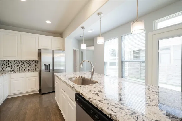 a kitchen with stainless steel appliances granite countertop a sink a stove and a refrigerator