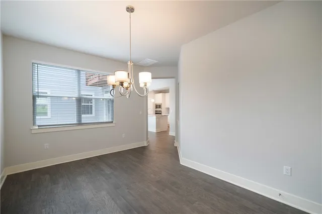 a view of a room with wooden floor chandelier and windows