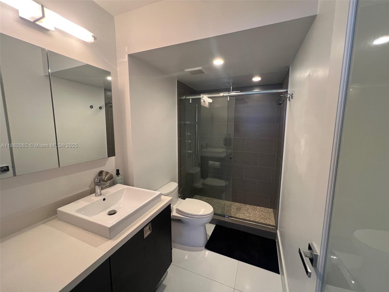 100 Lincoln Road, Unit 1022 Miami Beach, FL 33139 - Photo 35 of 63 a bathroom with a sink a toilet a mirror and shower