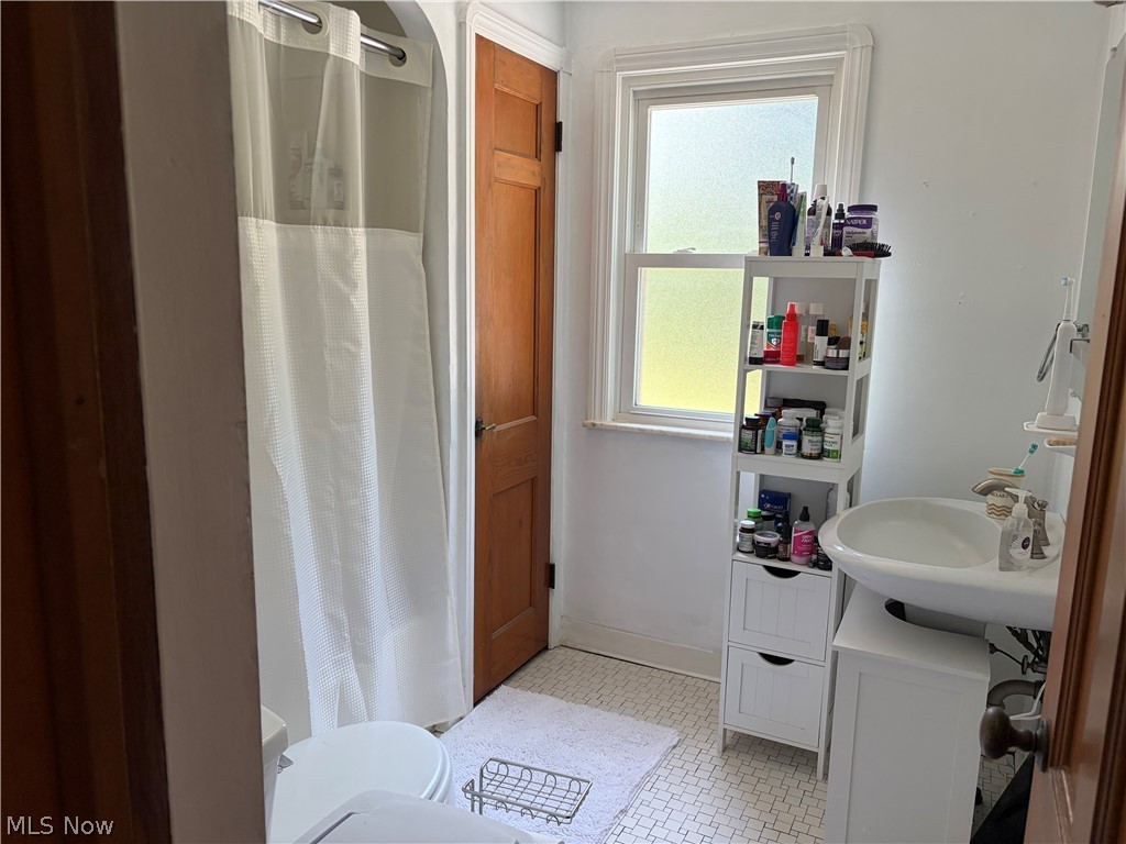 1604 Maplegrove Road South Euclid, OH 44121 - Photo 18 of 25 Bathroom featuring white hexagonal mosaic floor tiles, a window with frosted glass, and a pedestal sink